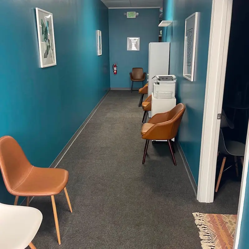 A commercial hallway with teal walls and leather waiting chairs, from the Clean Space Instagram