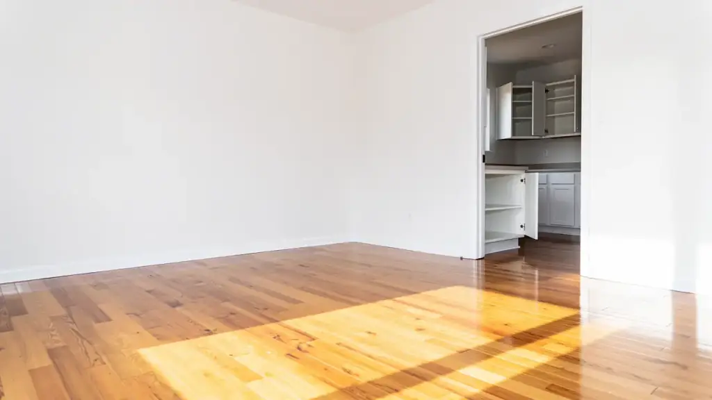 An empty house between owners, bare hardwood floors and open, emptied kitchen cabinets